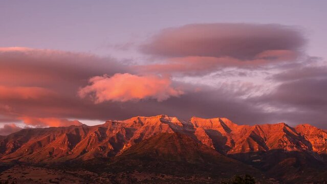 Sunset time lapse of mountain peak and clouds in bright color as clouds roll over Timpanogos.