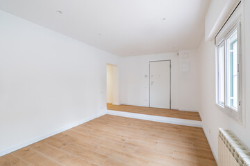 Empty clean room after renovation with white walls, window and wooden floor