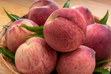 Fresh Peach fruits with leaves on bamboo basket, Korean white peach in Bamboo basket on wooden table.