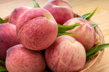 Fresh Peach fruits with leaves on bamboo basket, Korean white peach in Bamboo basket on wooden table.