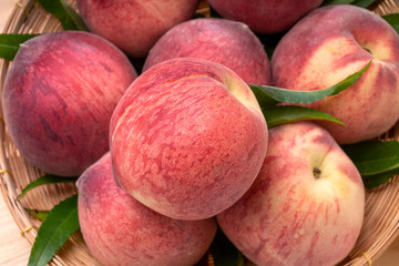 Fresh Peach fruits with leaves on bamboo basket, Korean white peach in Bamboo basket on wooden table.