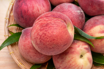 Fresh Peach fruits with leaves on bamboo basket, Korean white peach in Bamboo basket on wooden table.