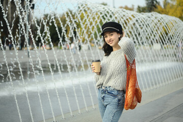 Young beautiful woman in orange sweater drinks coffee in cafe.