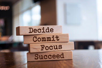 Motivational and inspirational quote Decide, commit, focus, succeed written on wooden blocks.