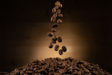 Roasted coffee beans falling against dark backdrop with light