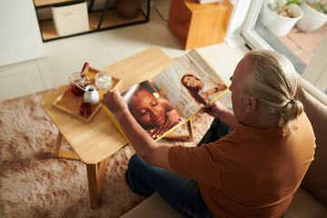 Aged man looking at photos in album publish by photographer