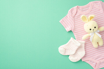 Baby concept. Top view photo of infant clothes pink bodysuit socks and knitted bunny toy on isolated teal background with copyspace