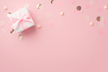 Gender party concept. Top view photo of white giftbox with bow small hearts and glowing confetti on isolated pastel pink background with copyspace