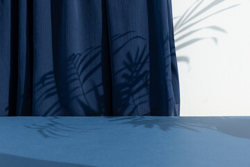 A scene with a blue curtain and the shadow of palm leaves. Premium podium for the presentation of a...