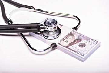 Medical concept - stethoscope over the dollar bills isolated on white background.