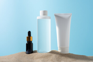 set of cosmetics, moisturizing cream on the sand on a blue background