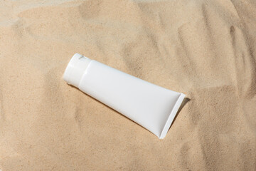 Clean, white tube of cream, moisturizer on the sand