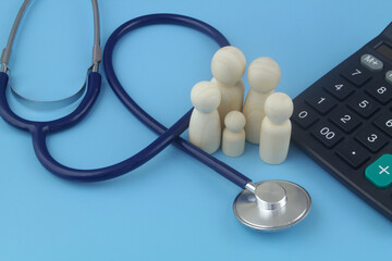 Cost of medicine and medical insurance for family. Wooden people figures with calculator and stethoscope on blue.
