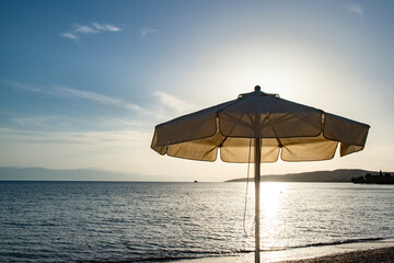 Beach umbrella at sunset on calm sea background