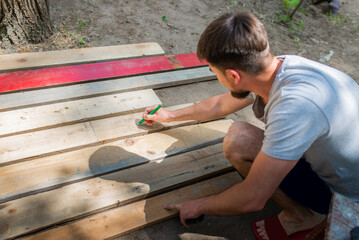 Male carpenter lays out a structure from wooden boards, close-up