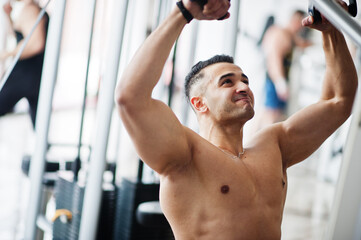 Muscular arab man training in modern gym. Fitness arabian men with naked torso doing exercises .