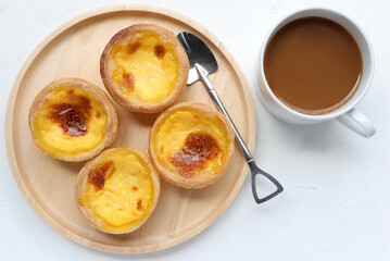 Delicious egg tart or portuguese egg tart on wooden plate with coffee on the table