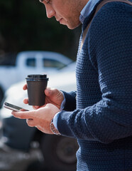 A young cheerful man on the go in the city drinking coffee.