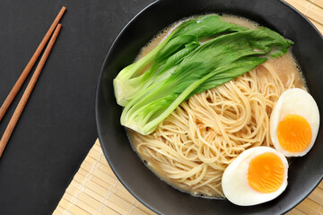 Delicious miso ramen noodles with egg in a bowl on a wood background.Top view, copy space for text