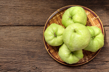 Close up of Fresh guava fruit on bamboo colander on the wooden table. empty space for text.