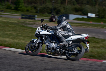 11-05-2021 Riga, Latvia Motorcyclist at sport bike rides by empty asphalt road. white sport bike....