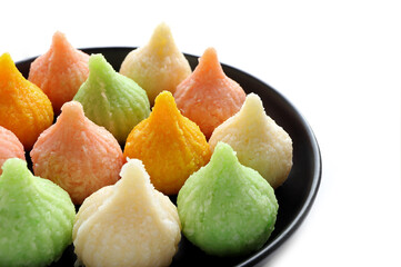 Close up of Indian sweet Motichoor Laddoo or Bundi Laddu. Sweet Tiranga coloured modak shape mithai or dumpling in a white plate. selective focus.