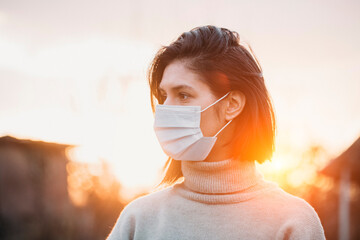 Portrait of a young woman in a medical mask. Young female patient patient stands against the backdrop of the wall, copy space for text. Pandemic