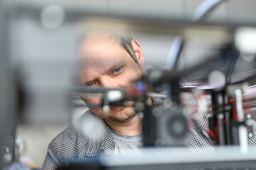 An engineer is setting up a machine for 3D printing, a printer for volumetric printing of parts.