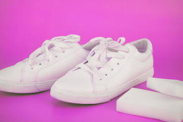 White sneakers cleaned with a melamine sponge on a pink background