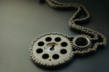 Gears from a car engine and a chain on a dark background.