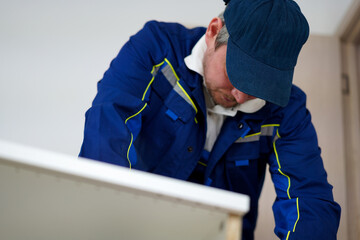 Handyman in uniform collects furniture. Help around the house, man power