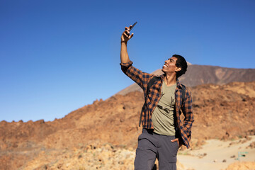 Young man taking selfie photo on a road trip. Man making memories on the mountain..