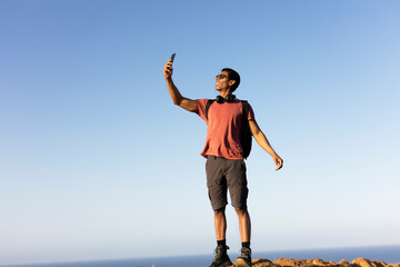 Young man taking selfie photo on a road trip. Man making memories on the mountain..