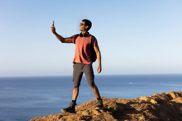 Young man taking selfie photo on a road trip. Man making memories on the mountain..