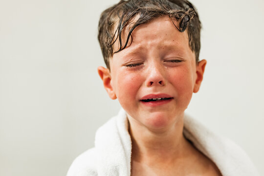 Sad boy with tears on face wrapped in white towel