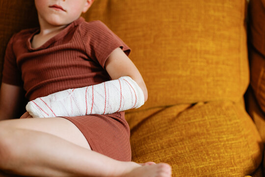 Anonymous cute boy with broken arm on couch