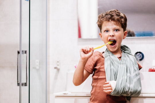 Boy with broken arm brushing teeth