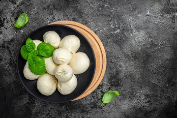 Traditional mozzarella cheese with fresh basil leaves on a dark background. Long banner format. top...