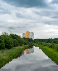 Fototapeta premium High-rise houses on the shore of a pond under a cloudy sky