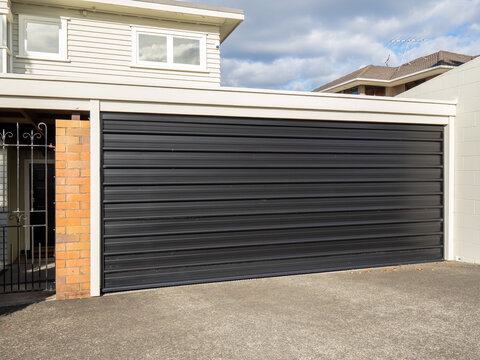 Garage with tilt-up retractable metal door painted black. Copy space stock photo.