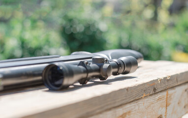 Obraz premium Sniper rifle lies on a wooden background. Optical sight close-up.