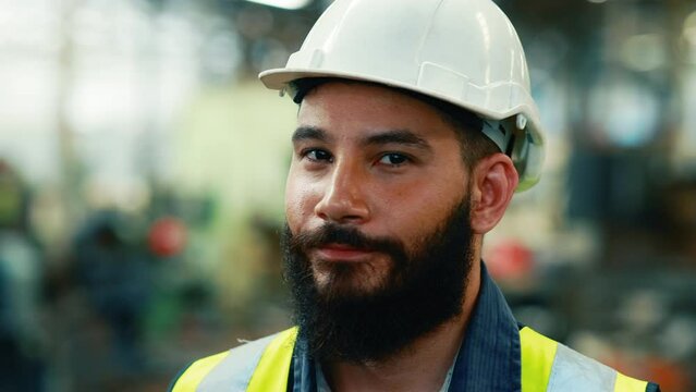 Slow motion. Portrait Professional mechanical engineering hispanic male in white safety hard hat helmet and look at camera at metal factory.