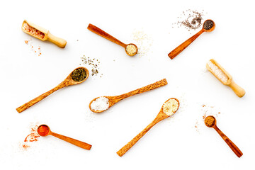 Variety of colorful spices and herbs in wooden spoons on kitchen table, top view