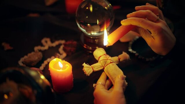 Occultist dripping hot wax on voodoo doll, magic rituals, black spell, horror