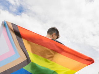 Pride day 2022. Young lesbian girl holding the lgbtq+ flag on the pride day. Celebrating the lgbt lesbian, gay, bisexual, transgender, queer and other identities rights.