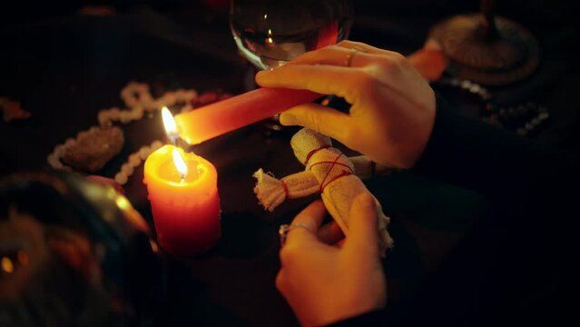 Black magician dripping hot candle wax on ragdoll, voodoo magic, dark spell