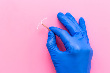 Fototapeta Doctor gynecologist holding intrauterine contraceptive device. T-shaped copper contraceptive obraz