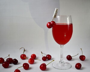 fruit drink in a glass and cherries on a white background