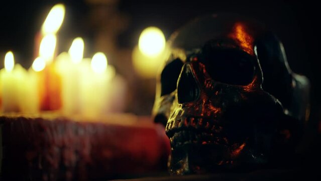 Spooky dark skull standing on table surrounded by burning candles, witchcraft