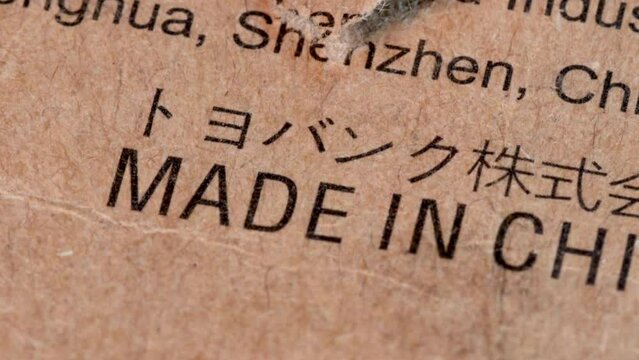 Made in China text on the surface of a cardboard box, paperboard surface with "Made in China" words in macro shot, close up view with rotating motion.